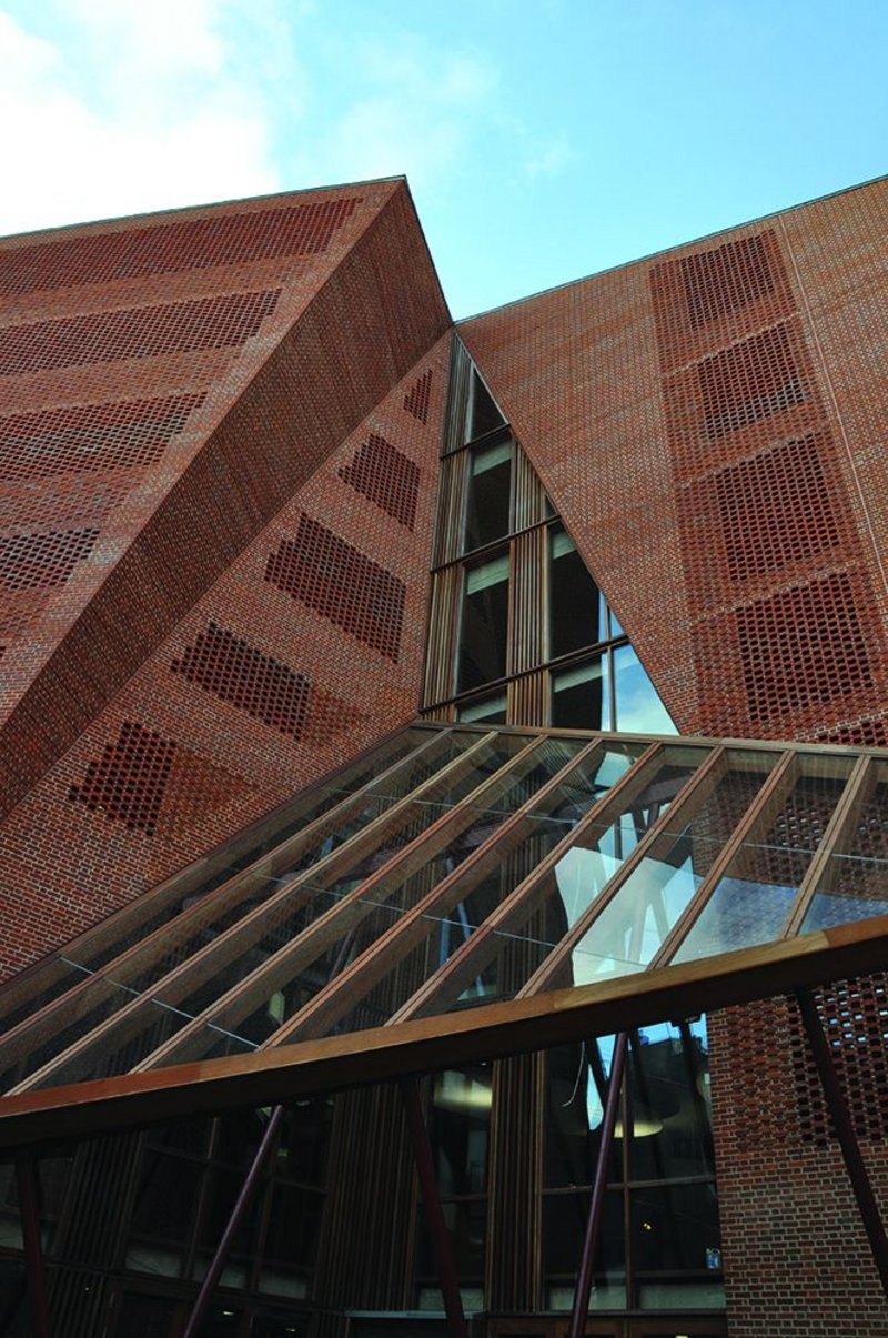 The building’s folded facade expands into perforated openings with glazing set behind, plus areas of ‘blind’ textured brickwork. All in handmade brick.