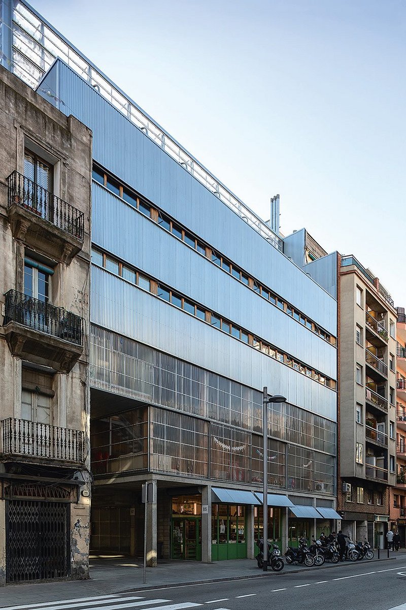 The sheer glazed north face of La Borda is counter-pointed on the south by deep balconies and orange blinds, part of its bioclimatic cooling strategy.