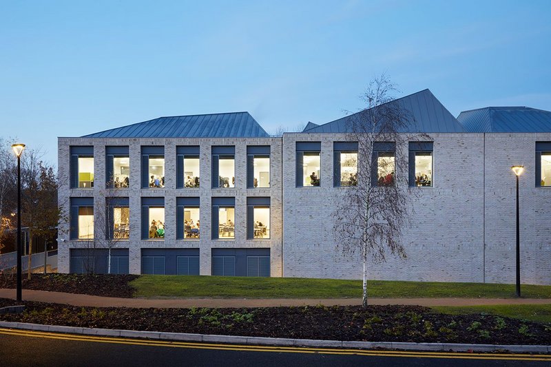 South elevation. Trabeated window openings give way to the textured brick wall of the rear of the large lecture theatre.