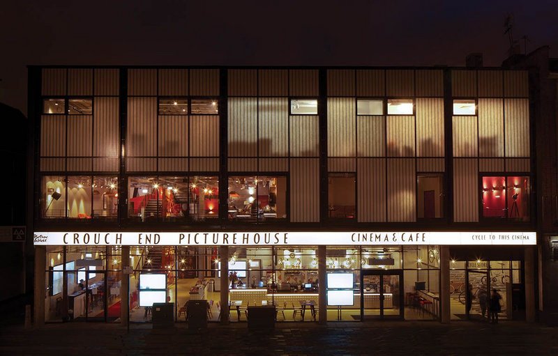 New partially-translucent Kalwall  sandwich panel cladding glows gently at night. The previously open ground floor is now glazed-in as a foyer.