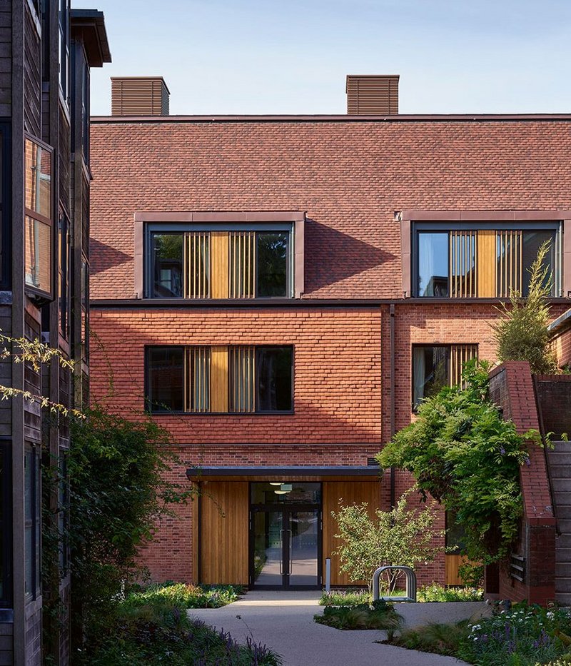 The new block inserts itself between earlier developments – most notably vHH’s 1990s dining hall on the right and the practice’s student dorms on the left, creating new adjacencies on the college site.