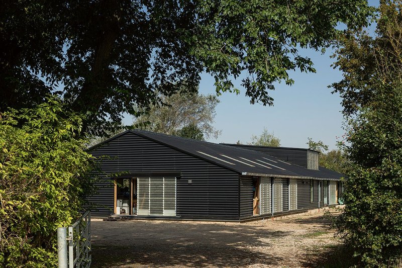 The gable of the building faces the road. Fiberglass roof lights and sliding doors bring the black cladding to life.