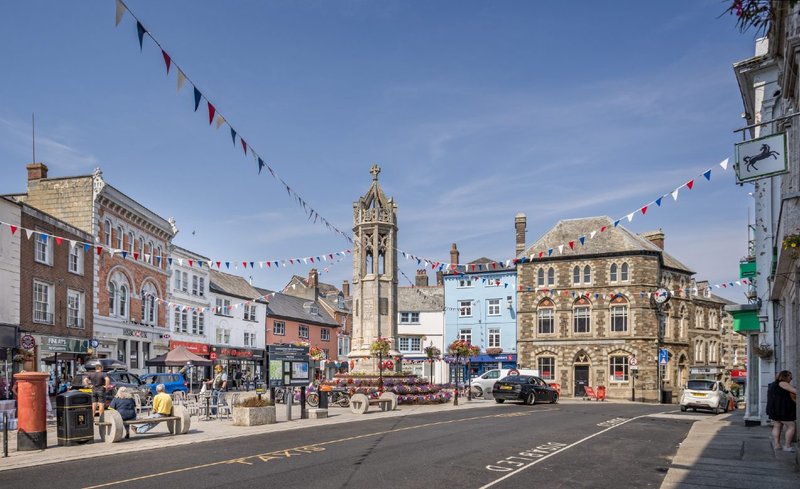 War memorial and market stalls in the centre of Launceston, Cornwall, 2022. The former Barclays bank is on the right.