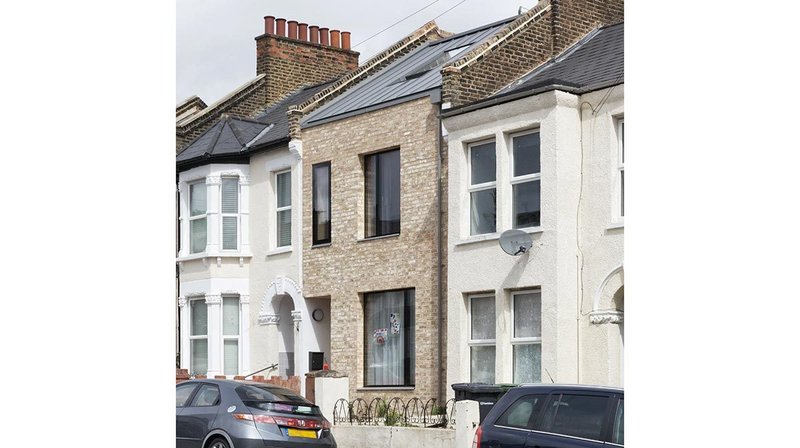 The front elevation mediates between its neighbours as well as picking up the brick along the street.