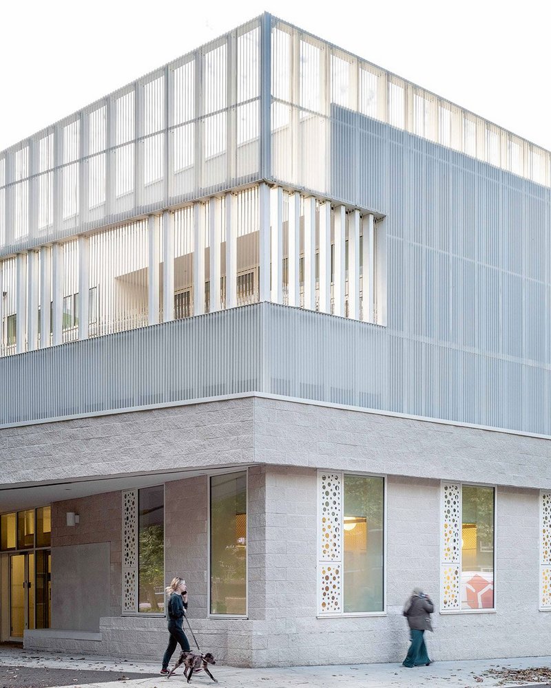 Above the street entrance lightweight metalwork screens learning terraces and makes a trellis for climbing plants.