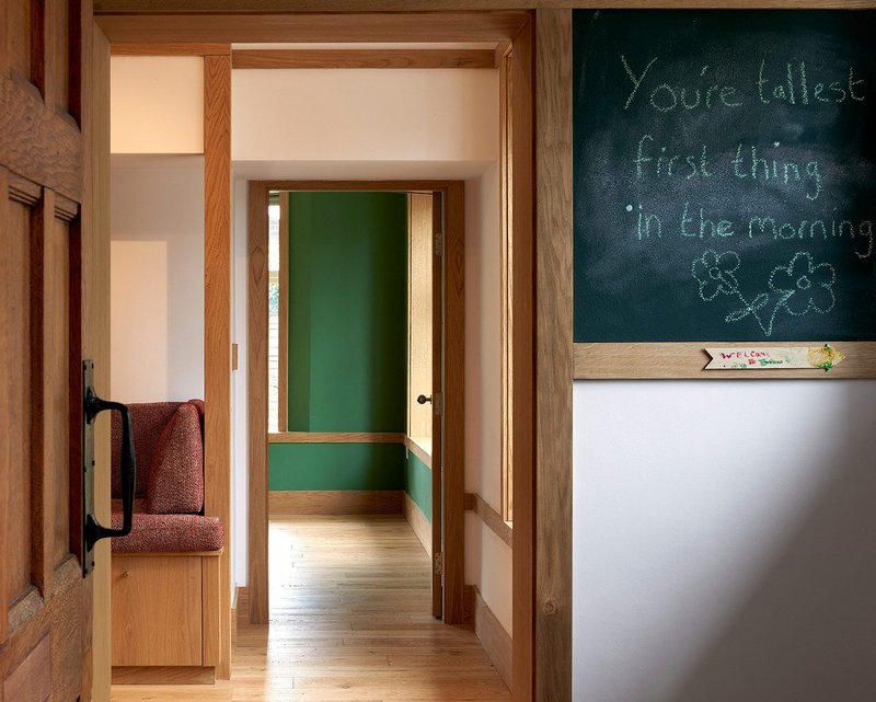 From the entrance to the home the calm green of the study is visible behind the oak doors and frames.