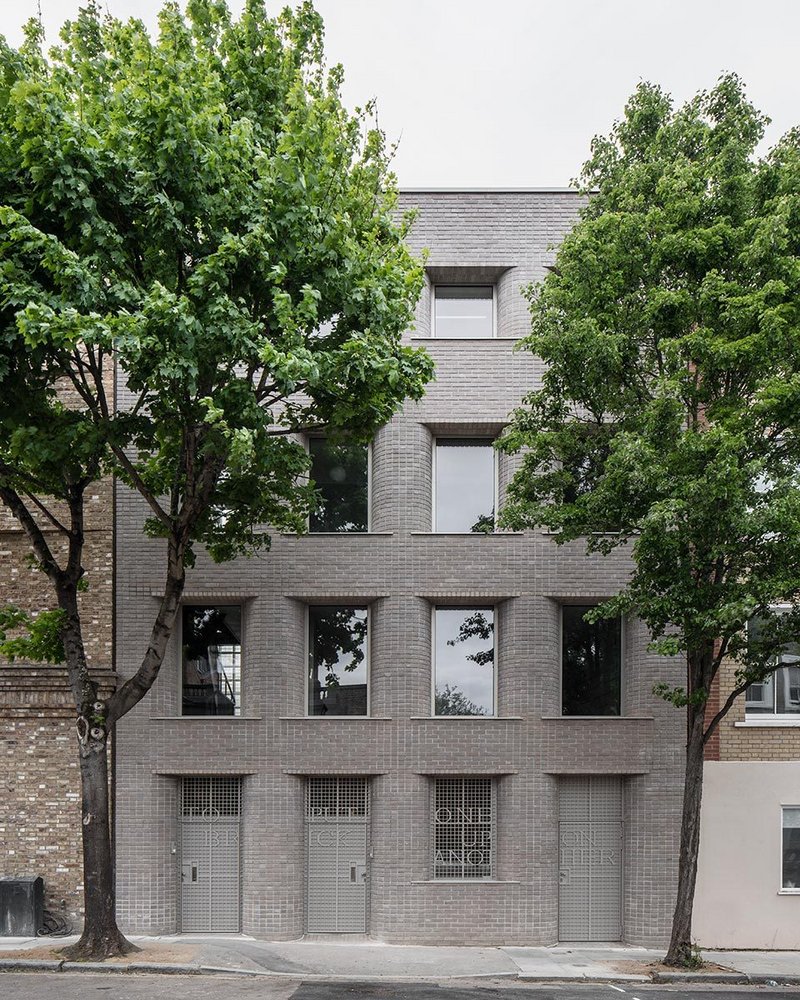 The grey brick facades is composed in a regular grid, picking up on the repetitive character of nearby housing.