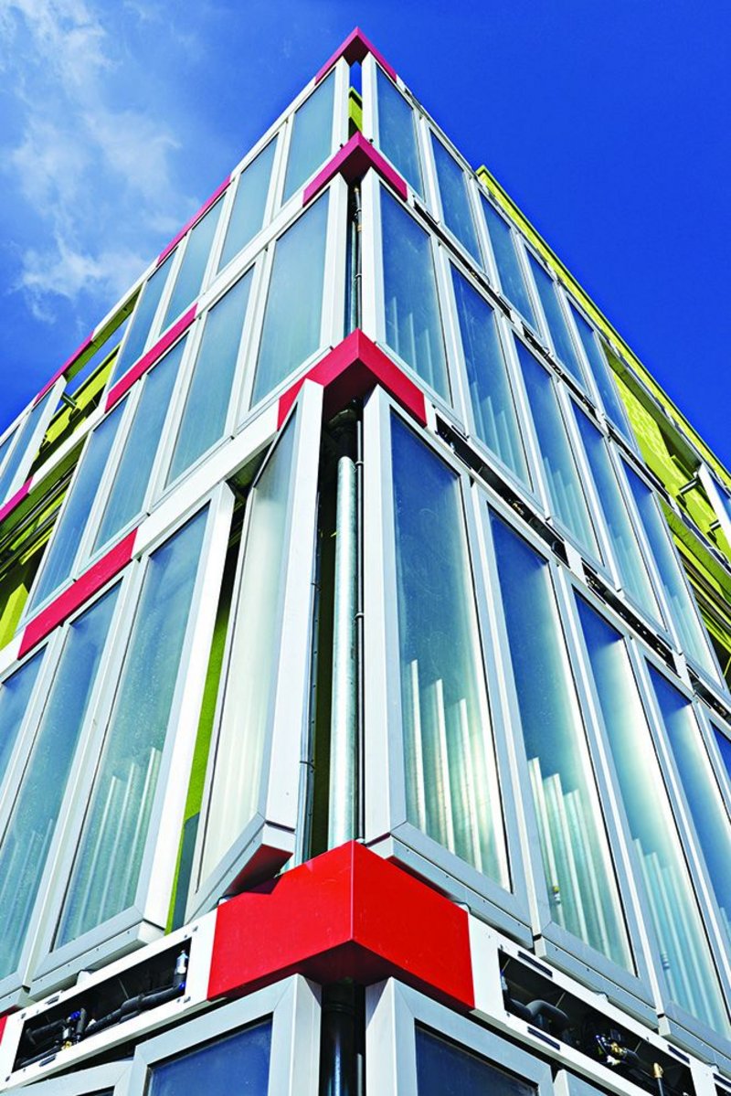 Algae panels, whose biomass pipe runs are hidden behind striking red metal panels, create a distinct look for the BIQ building.
