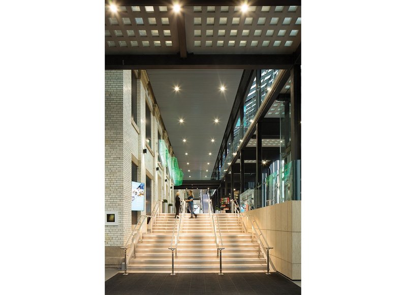 The new cinema concourse. Downlights are minimal, dramatic effects created with narrow beam luminaires on the glazed brick west wall of the town hall and LEDs in the handrails.