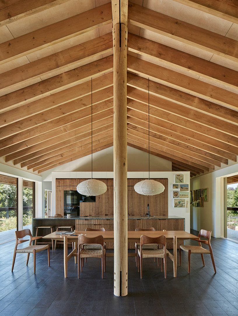 View past the green oak column in the living space to the walnut kitchen with its mezzanine above.