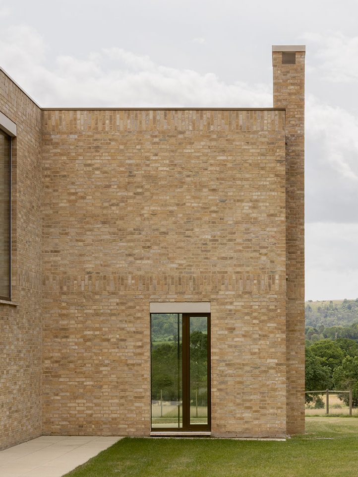 The buff brick house faces the humpback ridge of the South Downs.