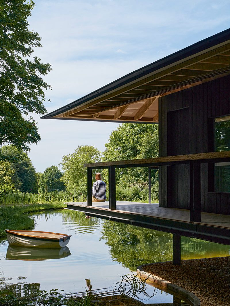 The wraparound walkway, covered by the low roof, is partially suspended over the lake.